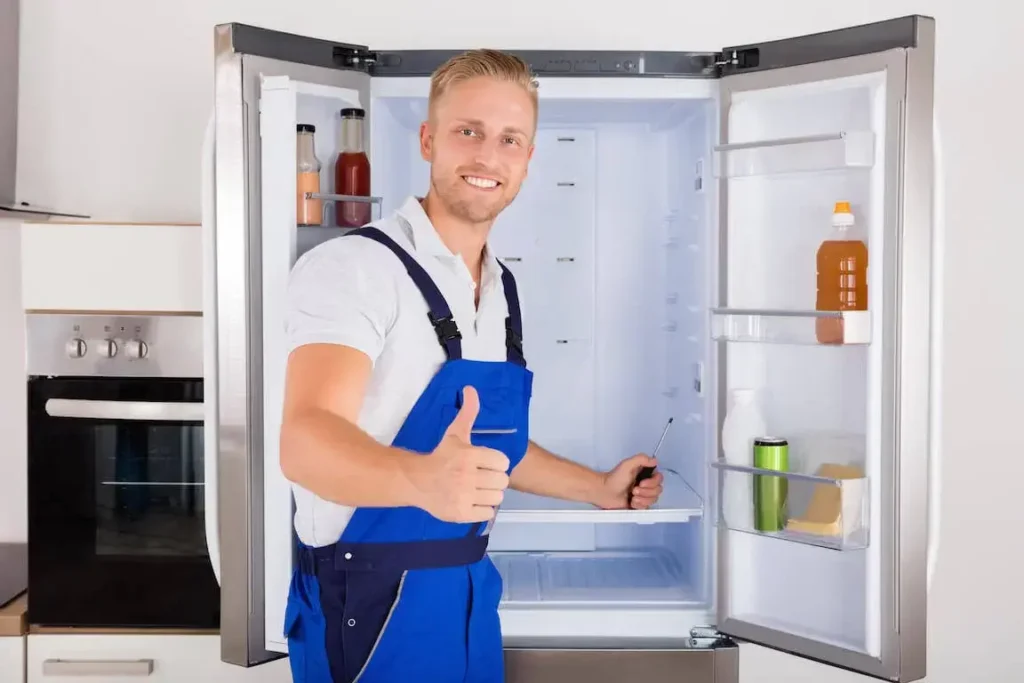 Happy technician giving thumbs up during refrigerator maintenance service in Salem OR