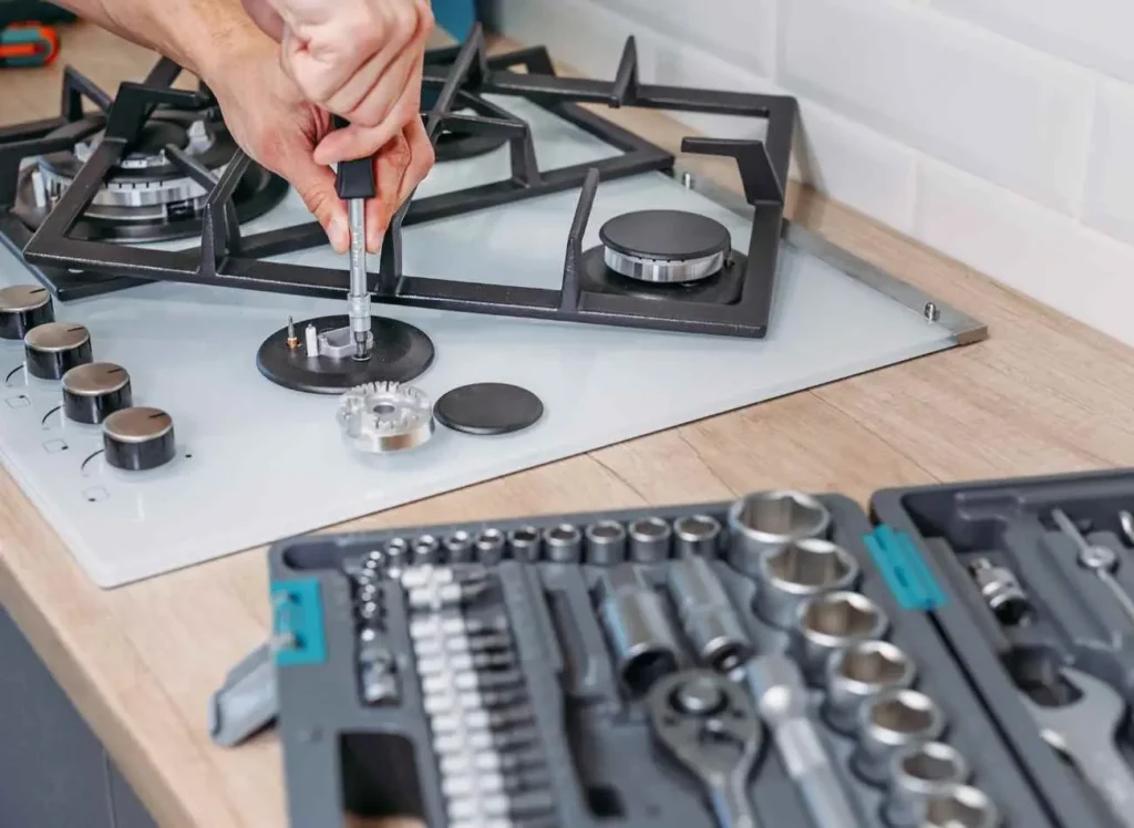 Technician repairing stove with professional tools during appliance repair service