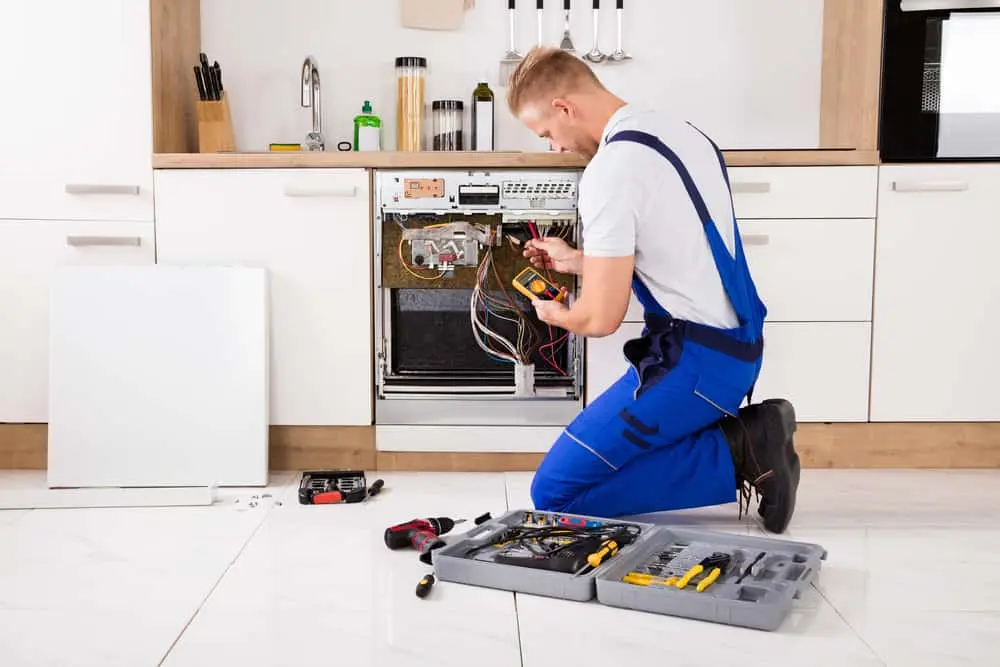 Technician repairing garbage disposal under kitchen sink