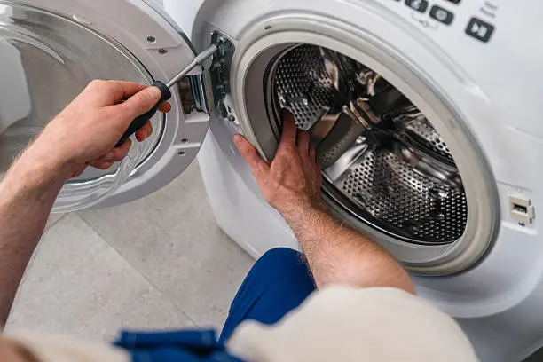 Skilled washer repair technician inspecting washing machine with tools in Salem Oregon